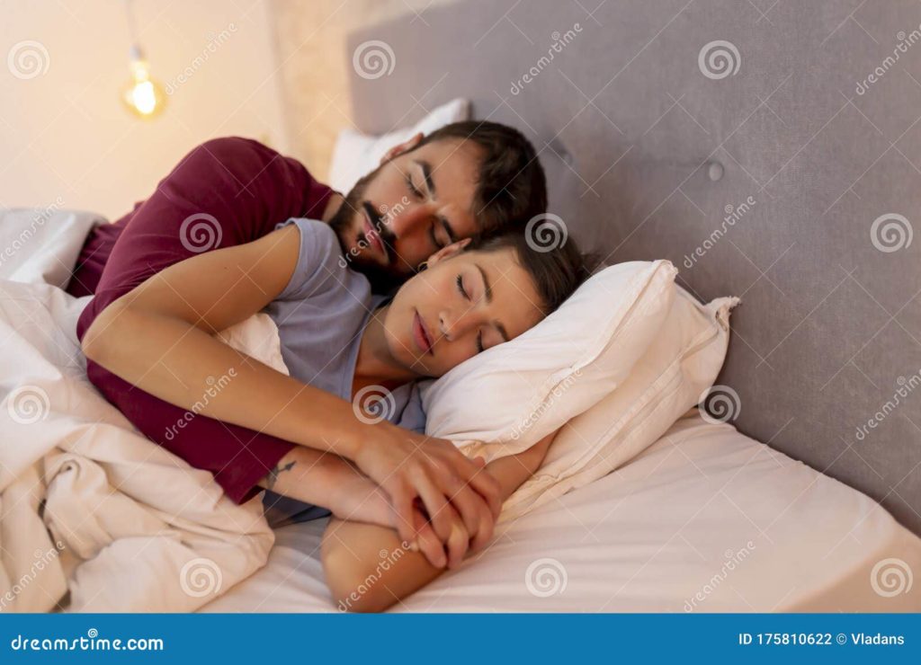 pareja enamorada usando pijamas tendidos abrazados en la cama durmiendo 175810622
